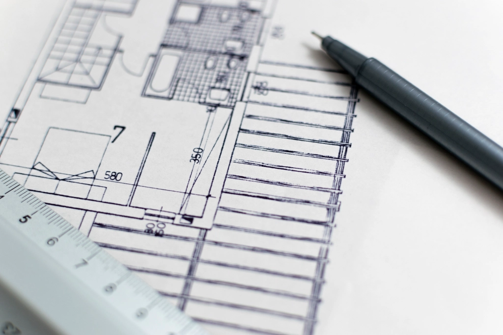 Closeup of pen and ruler on top of architectural floor plan.